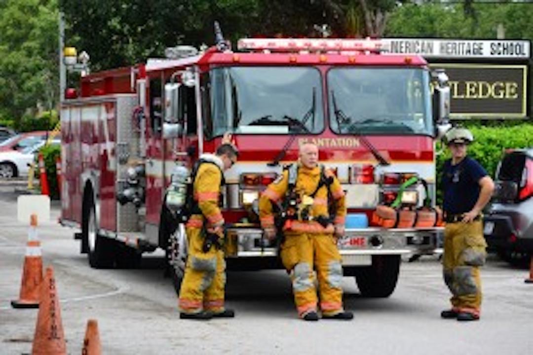Firemen of Plantation Fire Station 3 debrief in parking lot two.