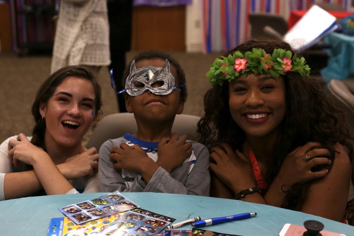 Senior Emma Quarequio dressed as Elsa and a hired actress as Moana pose with one of the patients at the arts and crafts table. (Photos/Angela Lin)