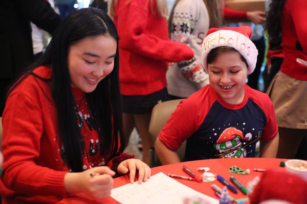 Heritage Boca junior Aida Wen helps a patient and party guest with arts and crafts. In addition to coloring, guests had the options to create their own ornaments and decorate gingerbread cookies. (Photo/Amber Bhutta and Angela Lin)